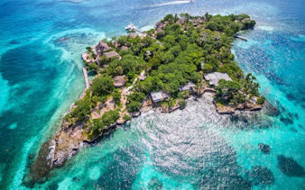 Aerial view of Isla del Pirata, lush greenery surrounded by turquoise waters, Rosario Islands, Colombia.