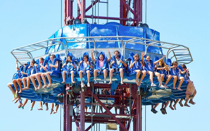 Tourists on El Desafío ride at Isla Mágica, Seville, experiencing a thrilling drop.