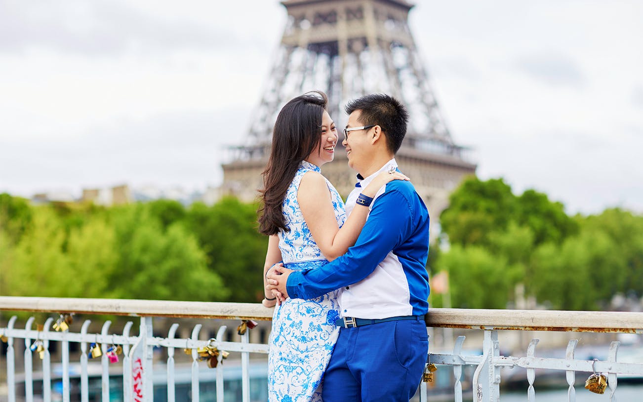 Couple embracing near Eiffel Tower in Paris during romantic photoshoot.