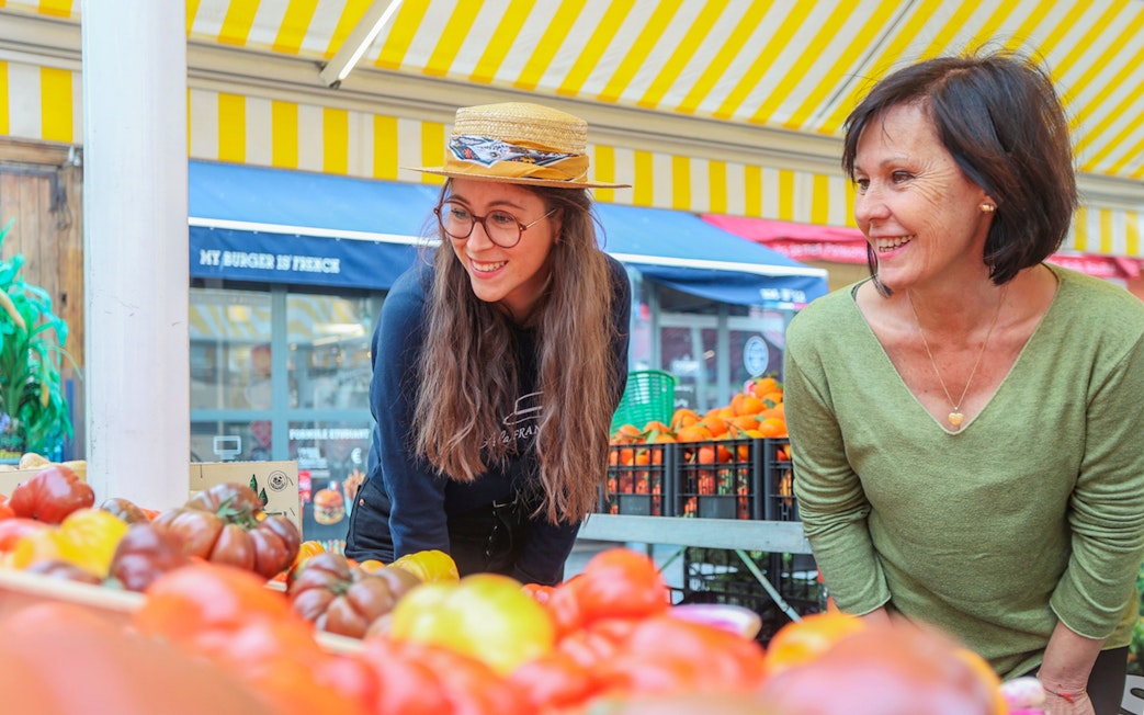 Women exploring a vibrant market in Nice during a walking and driving tour.