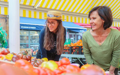 Women exploring a vibrant market in Nice during a walking and driving tour.