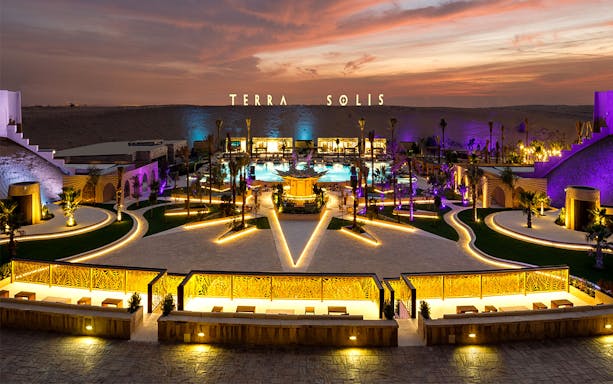 Terra Solis venue at sunset with illuminated pathways and central pool, Tomorrowland event location.