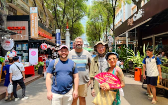 Group exploring a vibrant street with shops and cafes in Saigon, Ho Chi Minh City.
