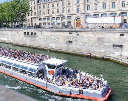Seine River cruise with people enjoying views of Paris landmarks.
