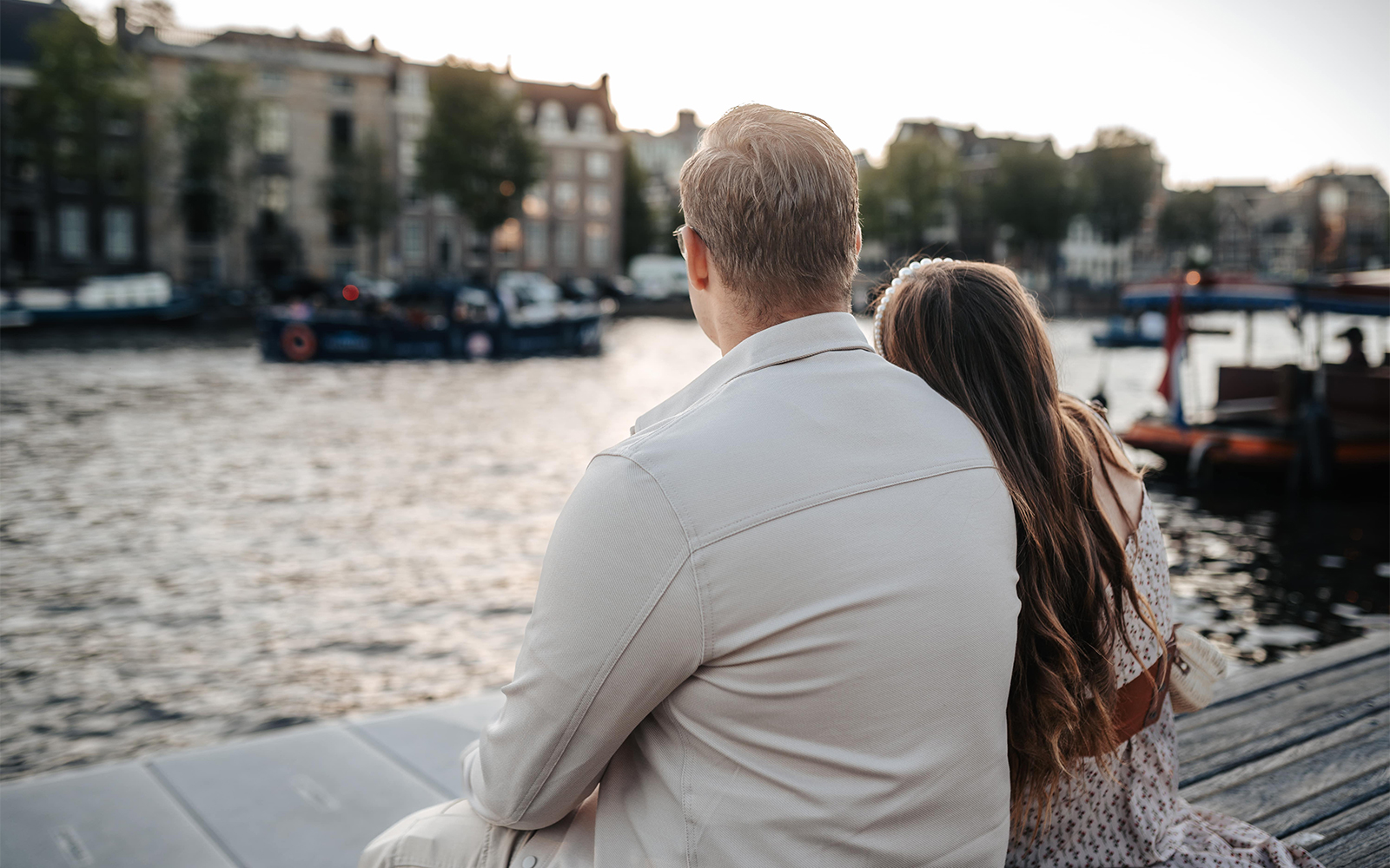 Couple sitting by the water near Magere Brug in Amsterdam during a professional photoshoot.