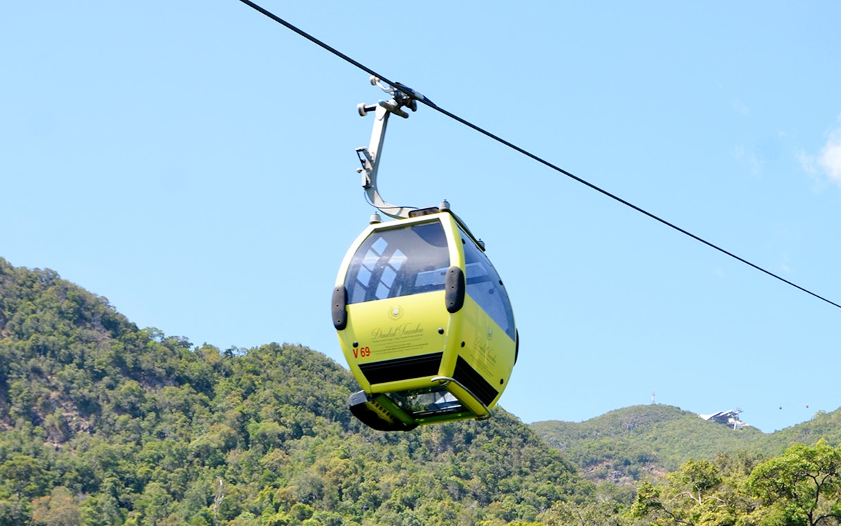 Langkawi cable car ascending over lush green hills.