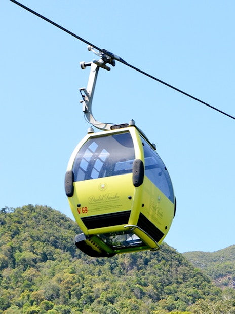 Langkawi cable car ascending over lush green hills.