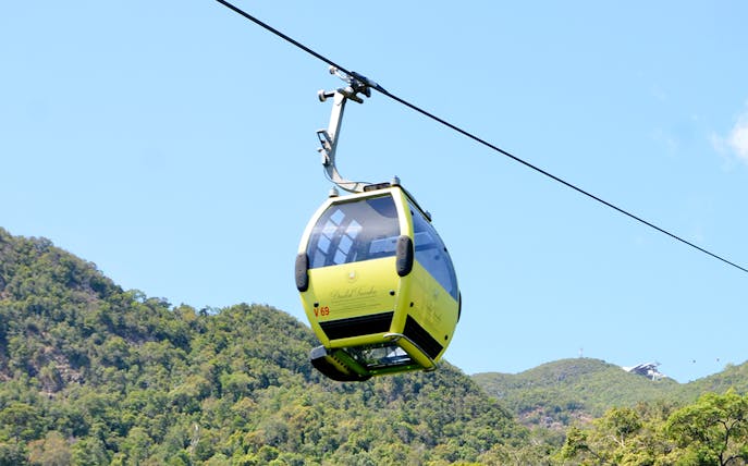 Langkawi cable car ascending over lush green hills.