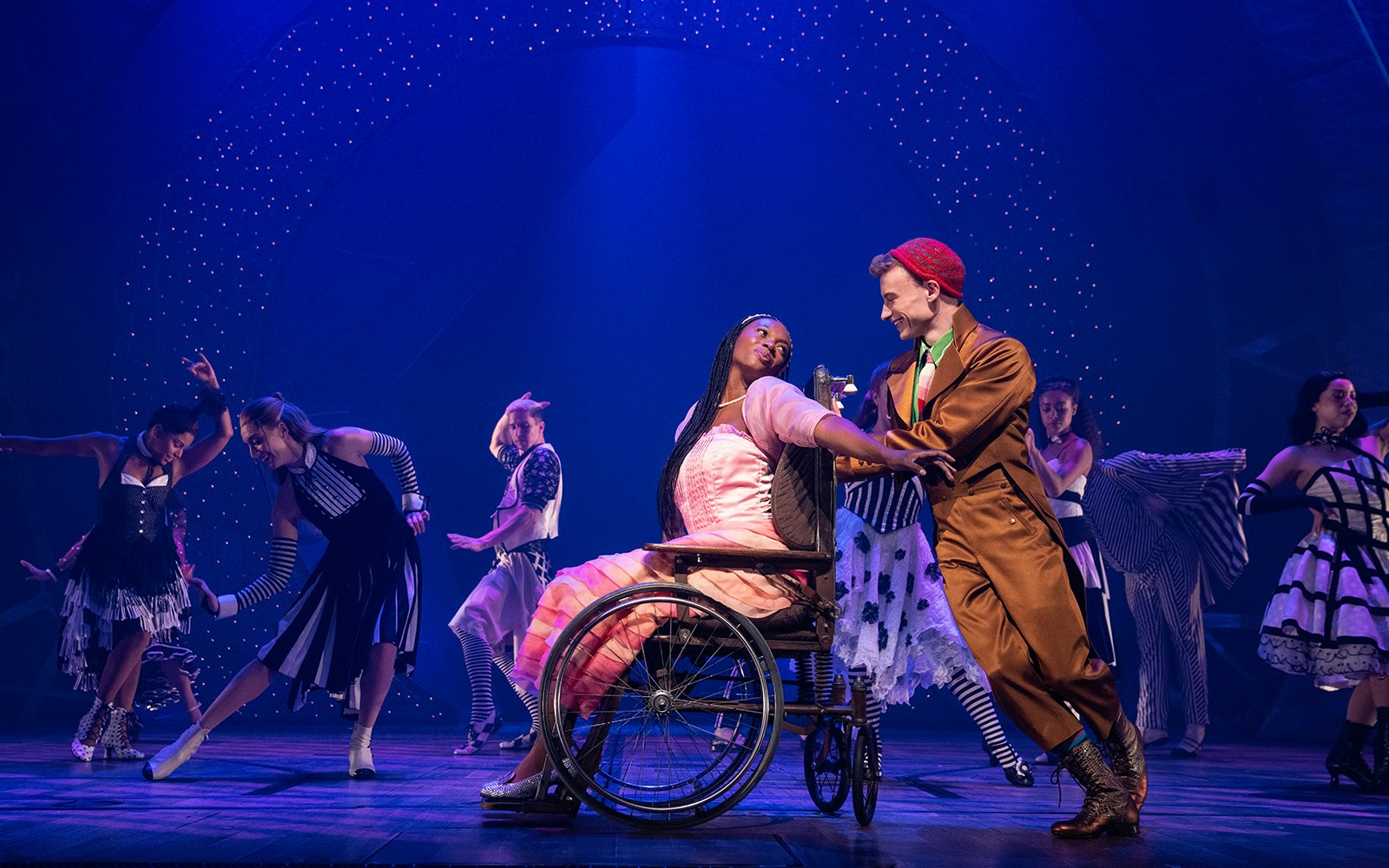 Performers dancing on stage during a scene from the musical Wicked.