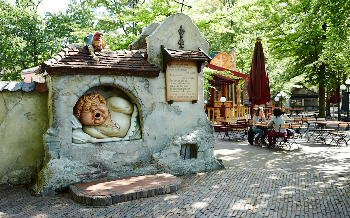Efteling theme park sculpture of a sleeping giant with visitors seated nearby.