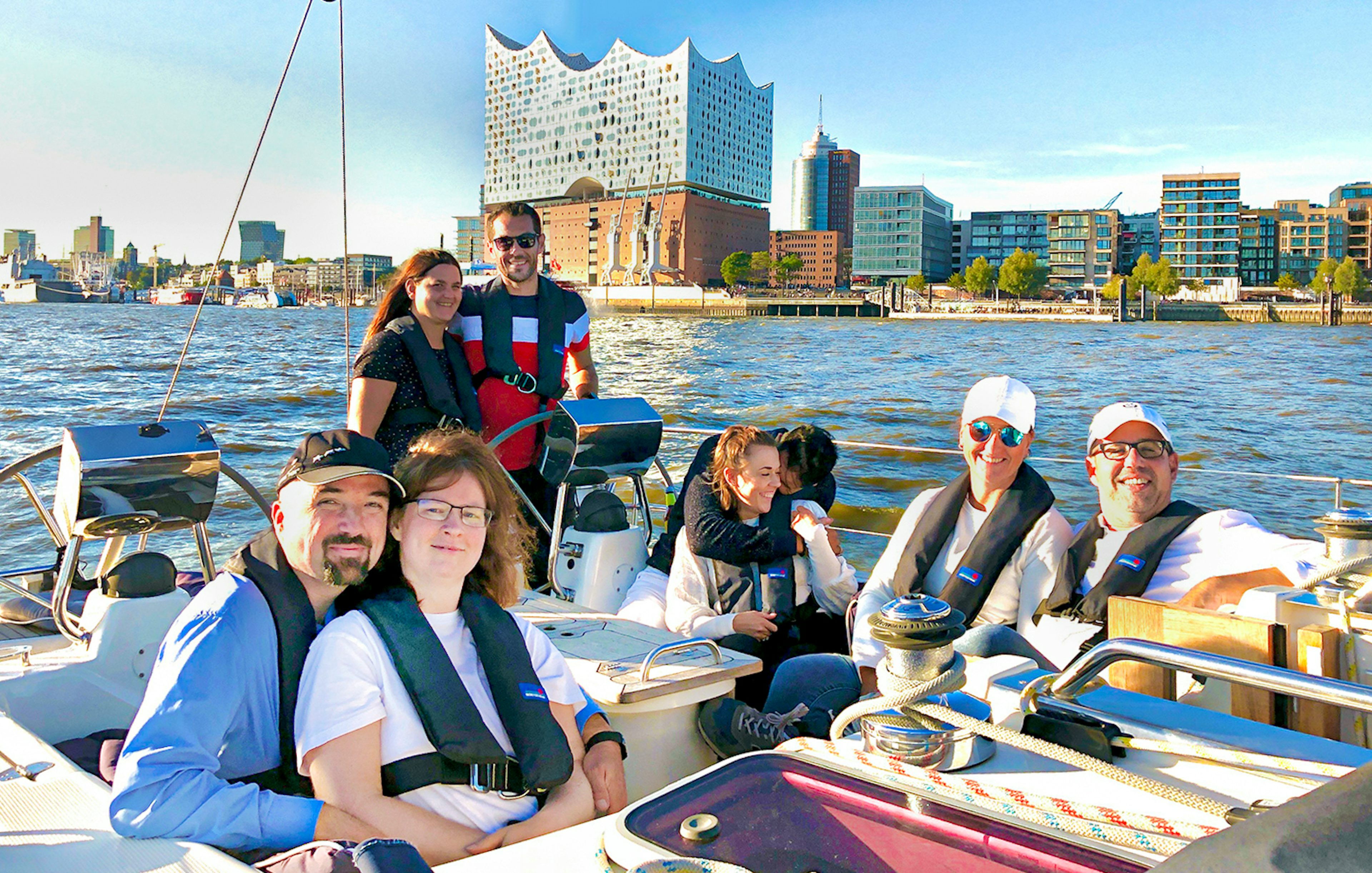 Group enjoying a sailing tour in the Port of Hamburg with Elbphilharmonie in the background.