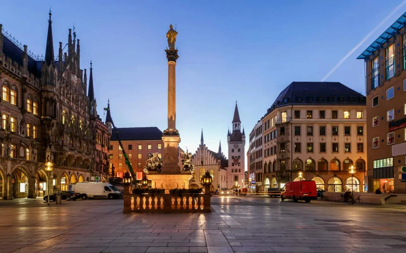 Marienplatz at dusk with illuminated buildings and Mariensäule, Munich.