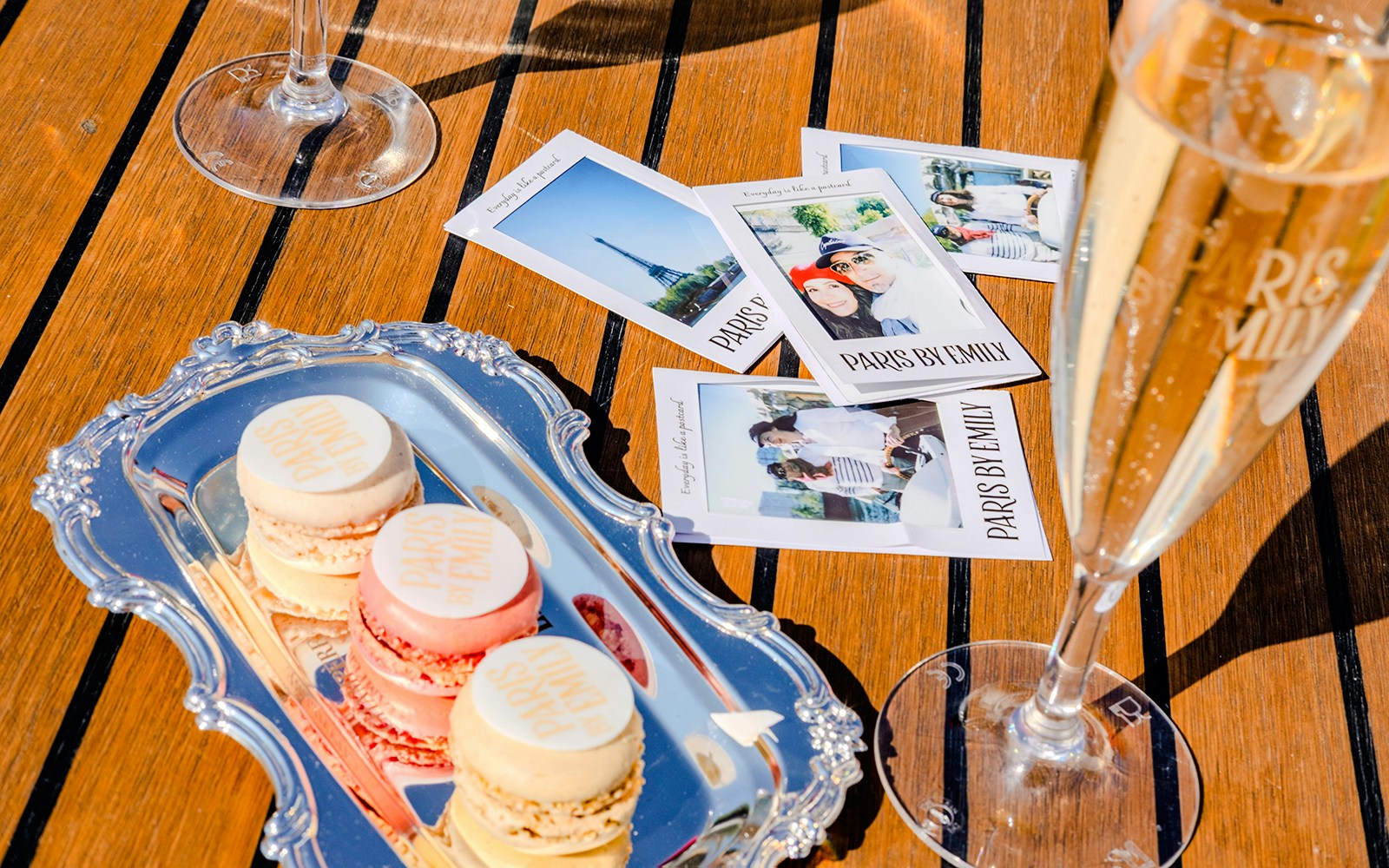 Champagne and macarons on a table with Paris-themed photos, Emily in Paris Seine Cruise.