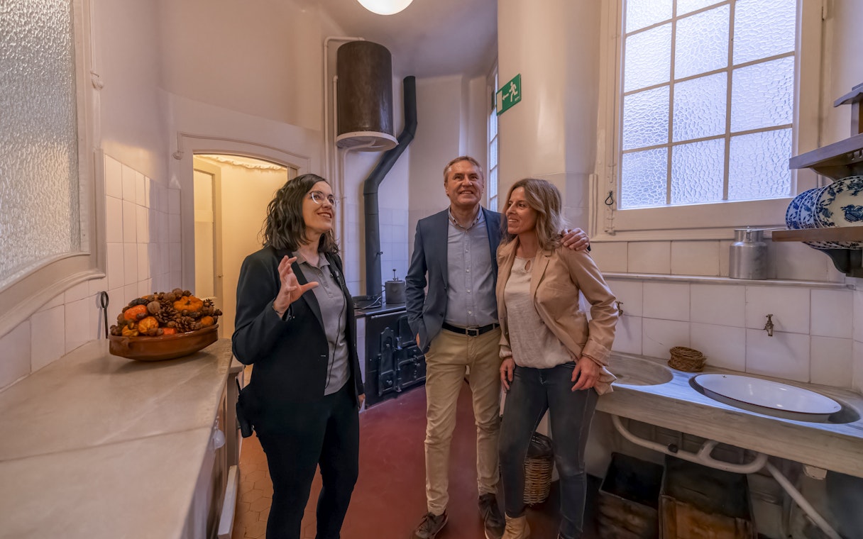 Tourist with guide exploring kitchen in Casa Mila, Barcelona.