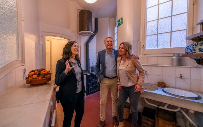 Tourist with guide exploring kitchen in Casa Mila, Barcelona.