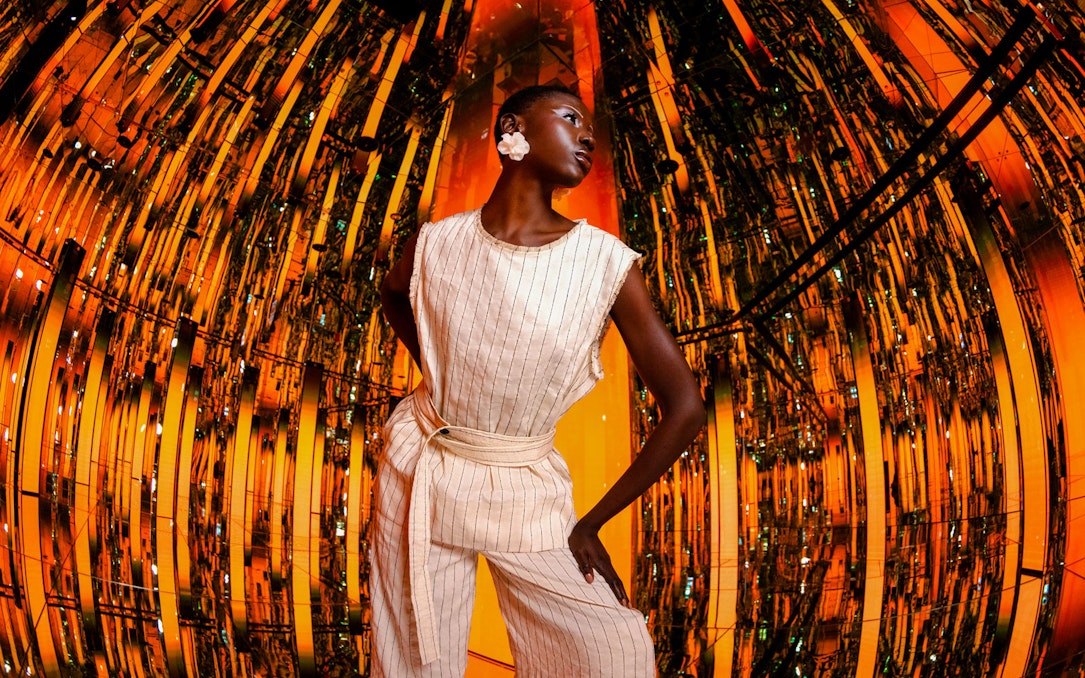 Person standing in a reflective, orange-lit room at AYA Universe.