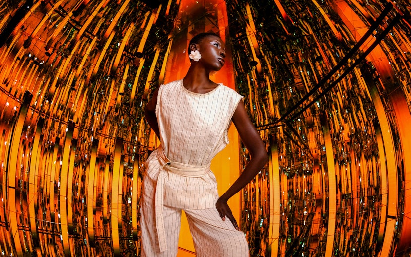 Person standing in a reflective, orange-lit room at AYA Universe.