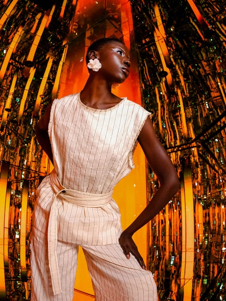Person standing in a reflective, orange-lit room at AYA Universe.