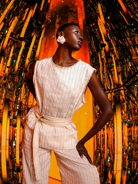 Person standing in a reflective, orange-lit room at AYA Universe.