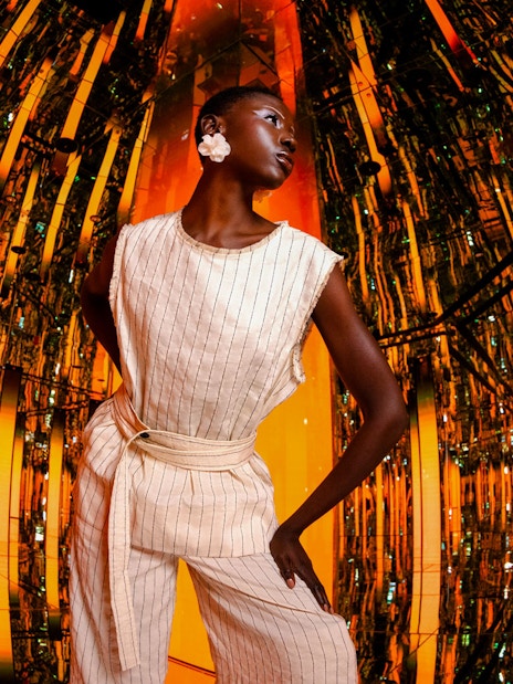 Person standing in a reflective, orange-lit room at AYA Universe.