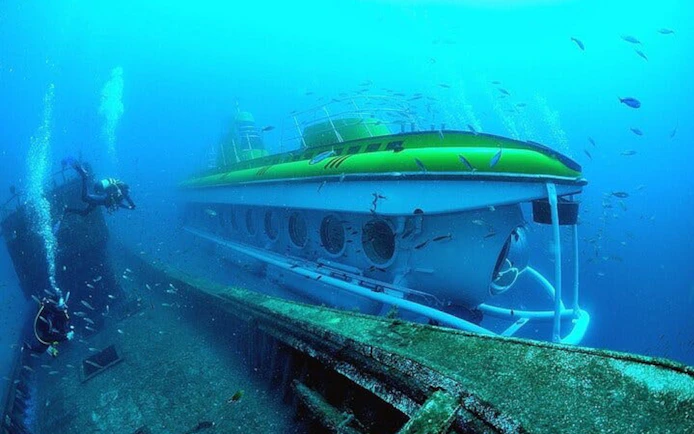 Submarine exploring underwater near shipwreck in Tenerife.