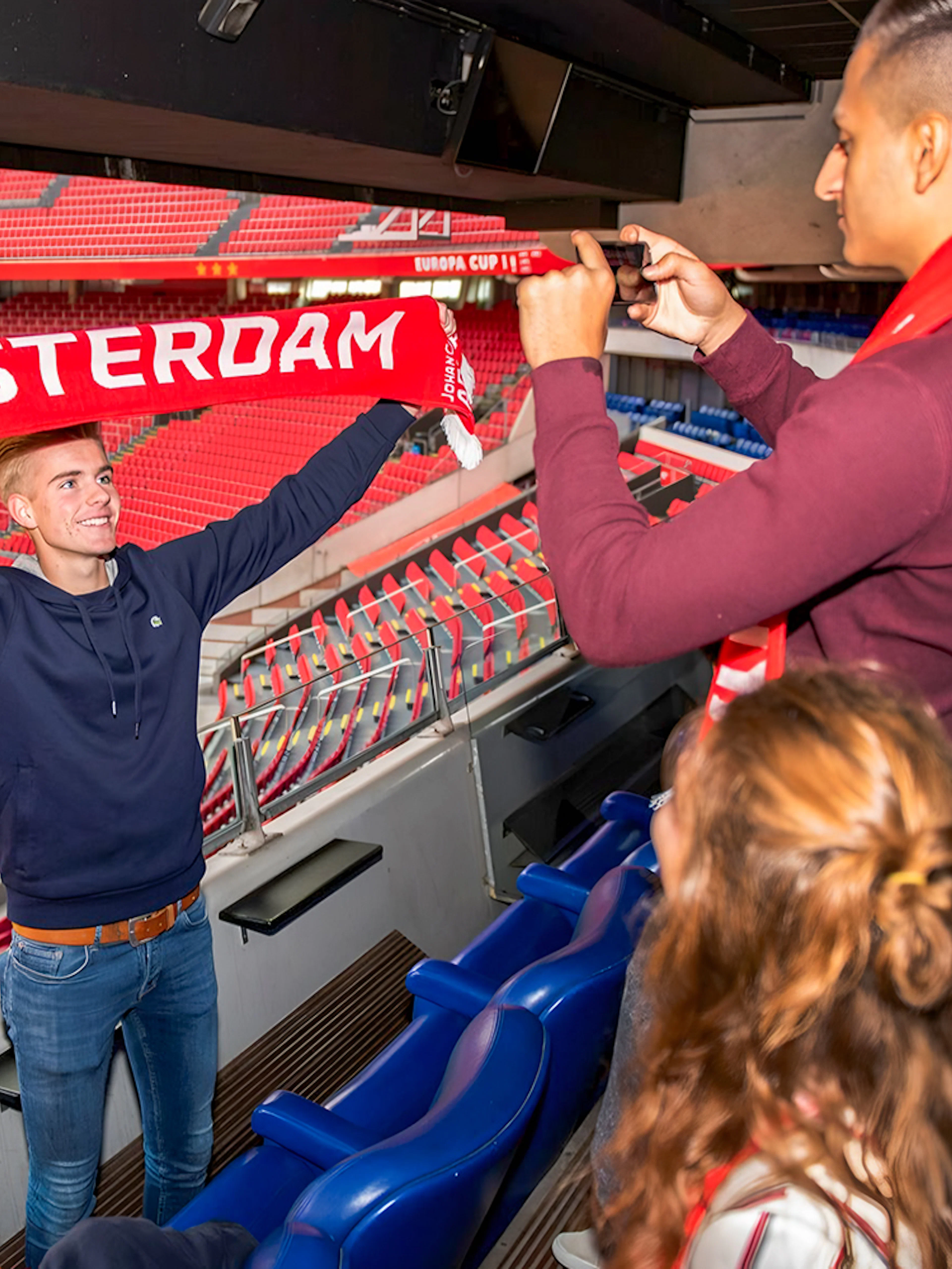 Man holding Amsterdam scarf at Johan Cruijff ArenA during VIP tour.