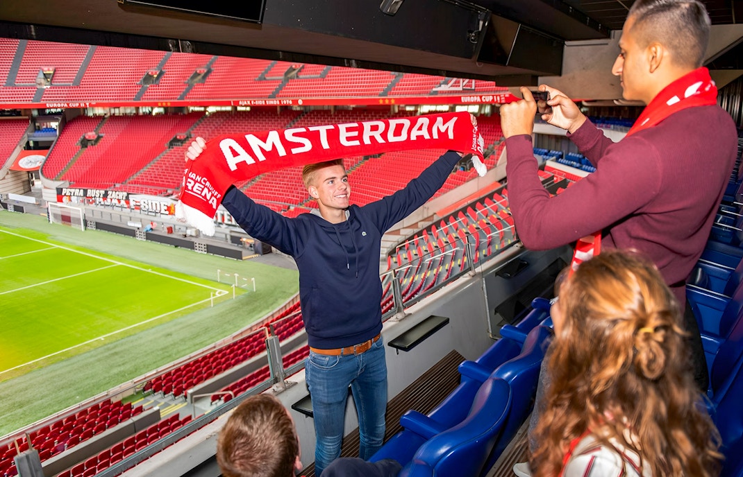Man holding Amsterdam scarf at Johan Cruijff ArenA during VIP tour.