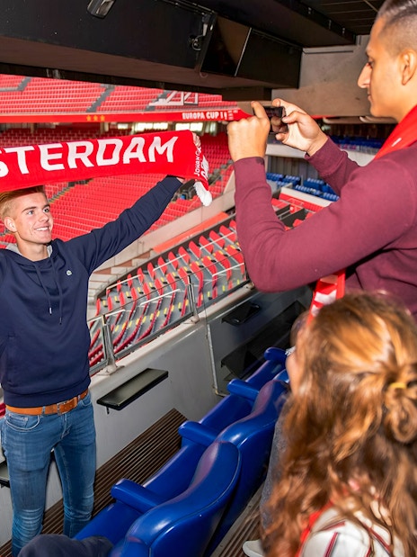 Man holding Amsterdam scarf at Johan Cruijff ArenA during VIP tour.