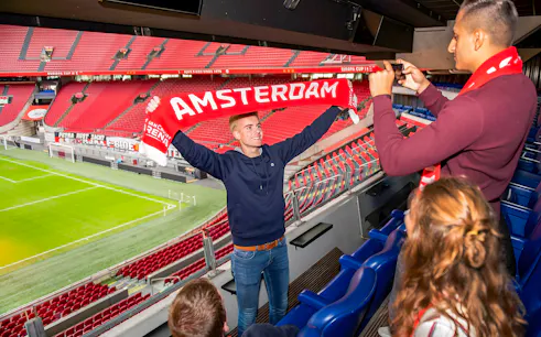 Man holding Amsterdam scarf at Johan Cruijff ArenA during VIP tour.