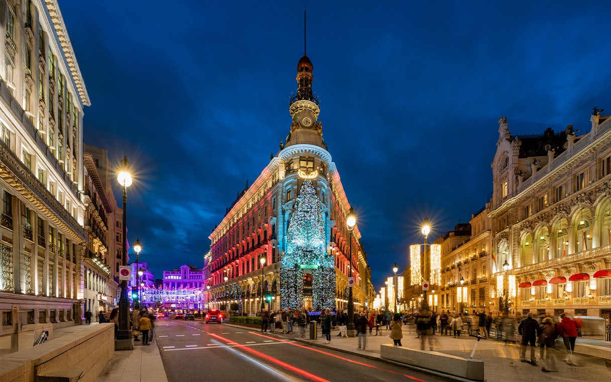 Four Seasons Hotel in Madrid adorned with Christmas lights at night.
