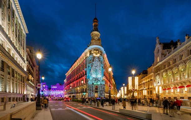 Four Seasons Hotel in Madrid adorned with Christmas lights at night.