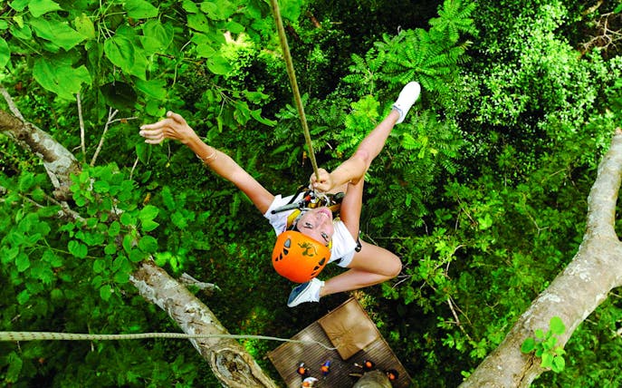 Ziplining through lush forest at Flying Hanuman, Phuket, with safety gear.