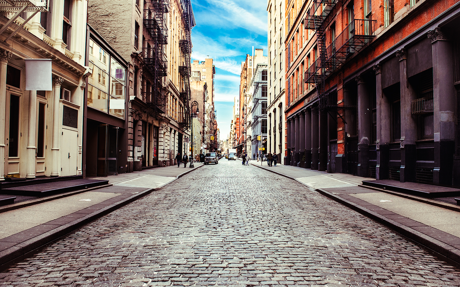 Cobblestone street in Stone Street, New York, lined with historic buildings and fire escapes.