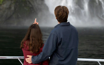 Couple admiring waterfalls on Milford Sound cruise, Queenstown tour.