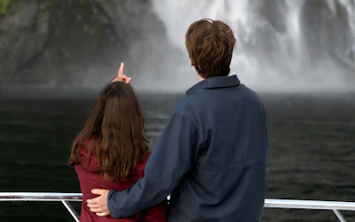 Couple admiring waterfalls on Milford Sound cruise, Queenstown tour.
