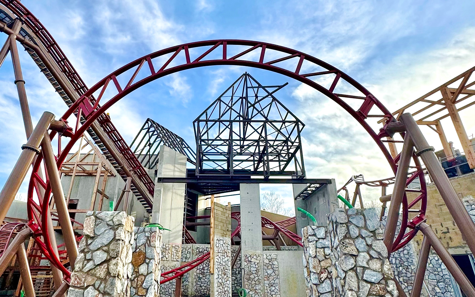 Cétautomatix ride structure at Parc Astérix, featuring red roller coaster tracks and stone pillars.