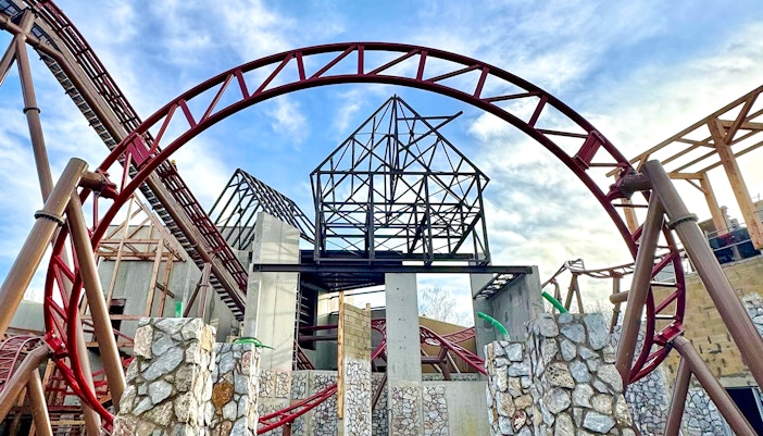 Cétautomatix ride structure at Parc Astérix, featuring red roller coaster tracks and stone pillars.