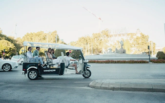 Tourists on an electric tuk-tuk near Cibeles Fountain in Madrid.