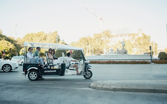 Tourists on an electric tuk-tuk near Cibeles Fountain in Madrid.