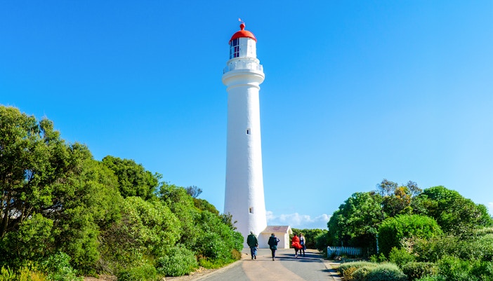 Splits Point Lighthouse with people walking along the coastal path, Aireys Inlet, Australia.