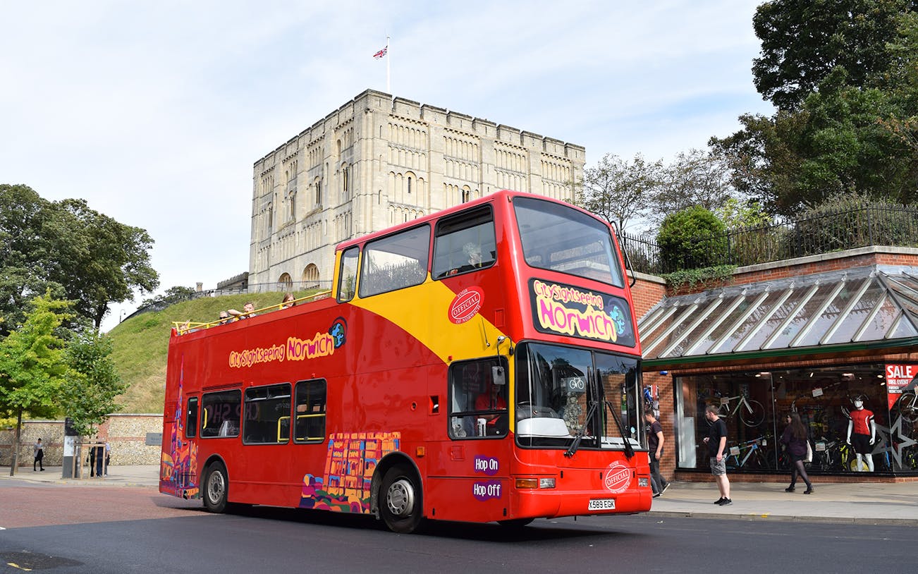Open-top sightseeing bus in front of Norwich Castle on a 24-hour hop-on hop-off tour.