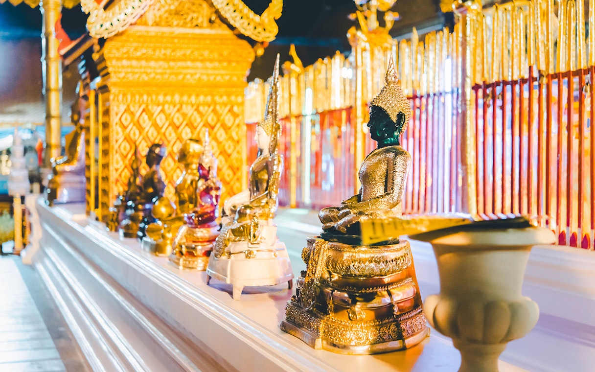 Buddha statues at Wat Phra That Doi Suthep, Chiang Mai, with intricate golden details.