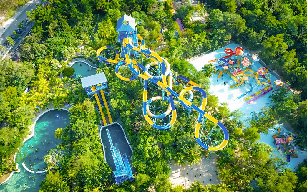 Aerial view of water slides and pools at Escape Penang water park surrounded by lush greenery.