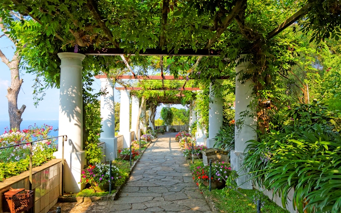 Pathway through lush garden with columns on Capri Island, Italy.