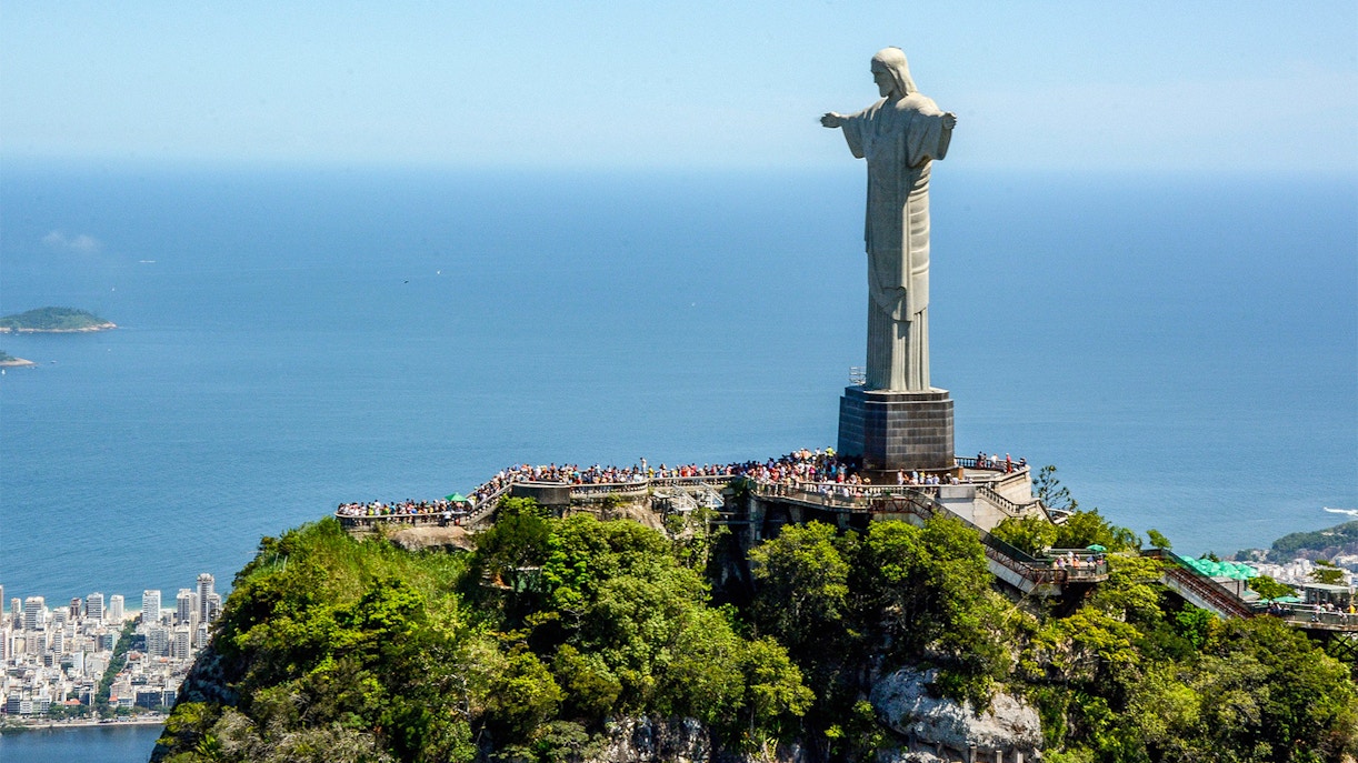 Christ the Redeemer statue overlooking Rio de Janeiro with Sugarloaf Mountain in the background.