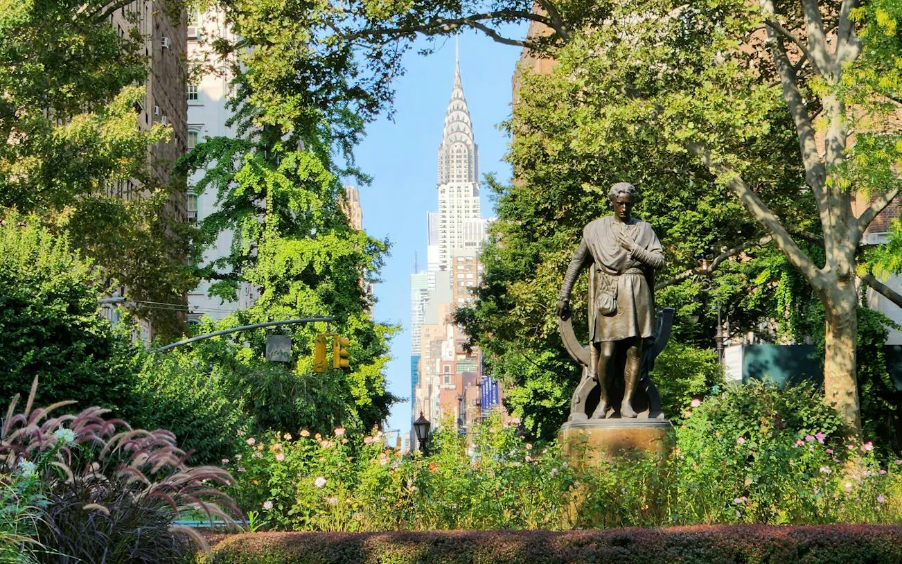 Statue in a New York park with the Chrysler Building in the background.