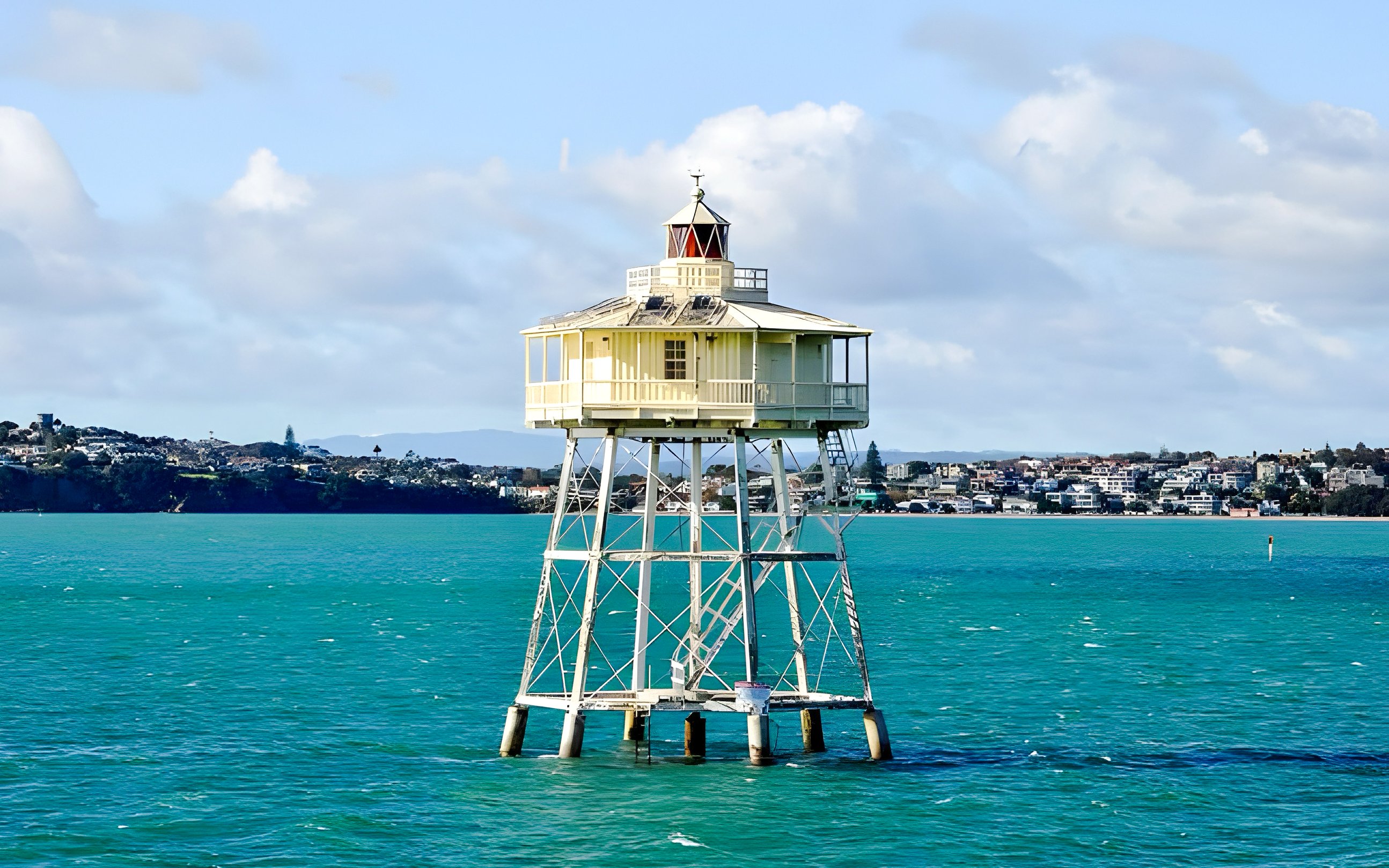 Auckland harbour lighthouse with cityscape in the background.