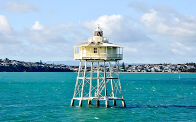 Auckland harbour lighthouse with cityscape in the background.