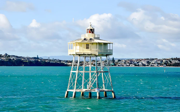 Auckland harbour lighthouse with cityscape in the background.