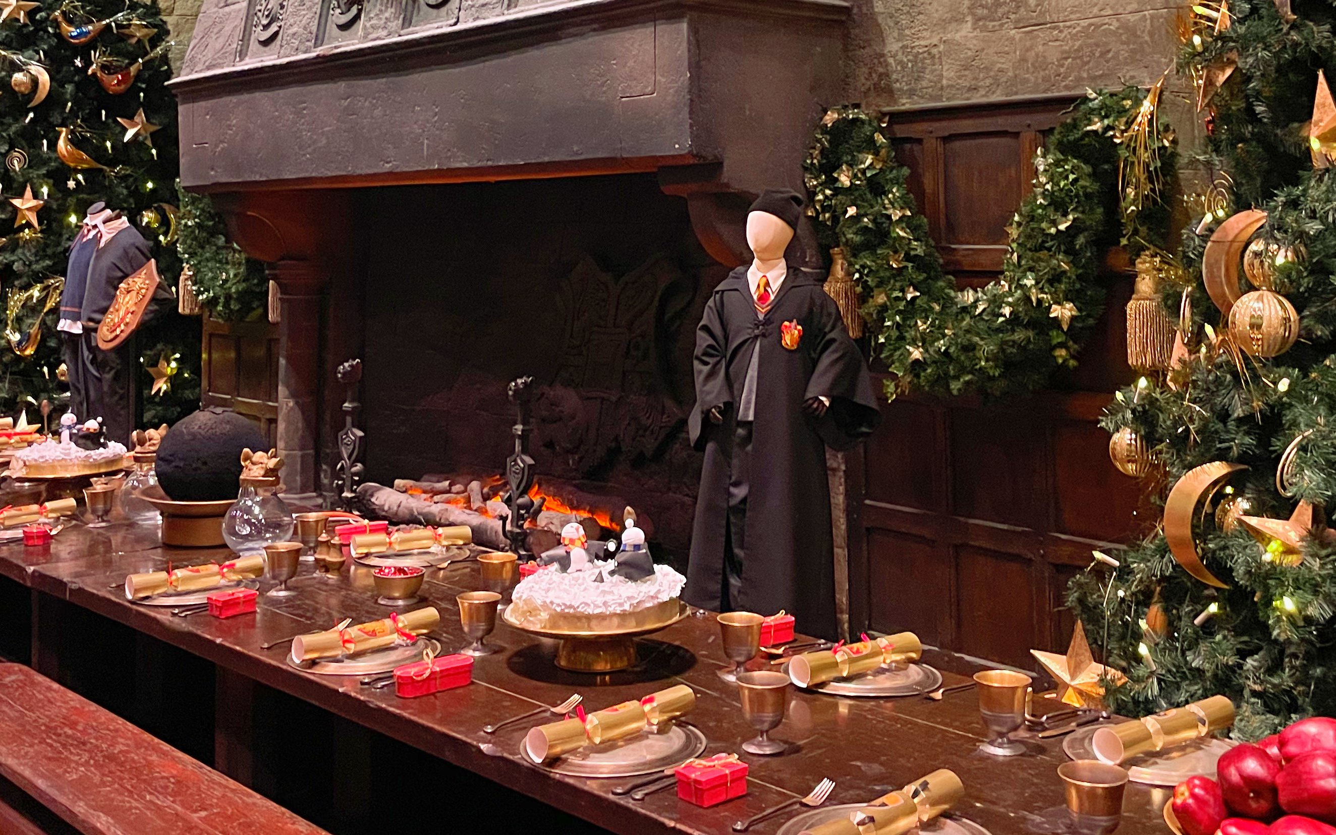 Hogwarts dining hall with festive decorations and a Gryffindor robe on display.
